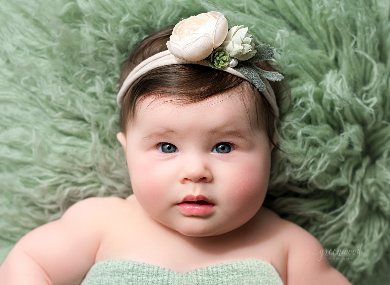 Baby girl on green rug with headband