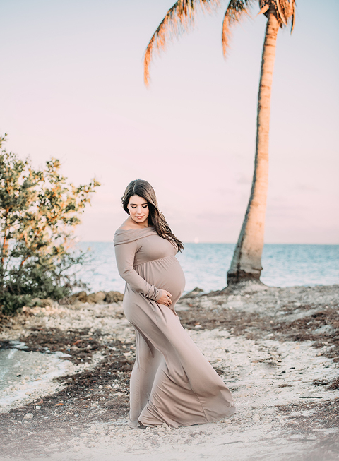 Expectant mother in taupe maternity gown by the beach