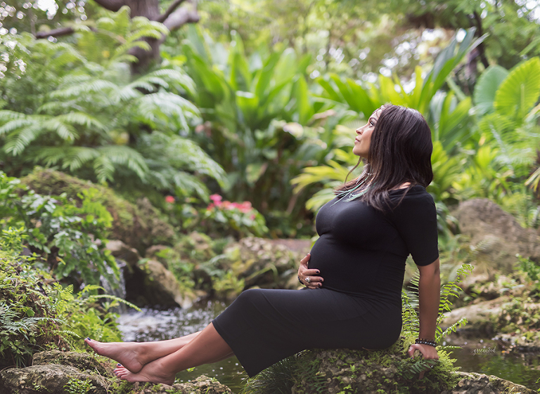 Expectant mother posed sitting on rock