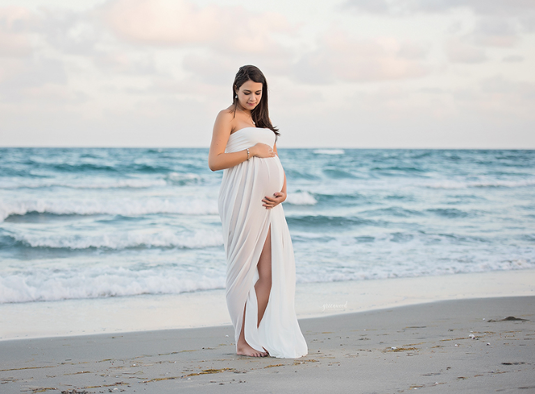 Pregnant mother posed in white gown at the beach