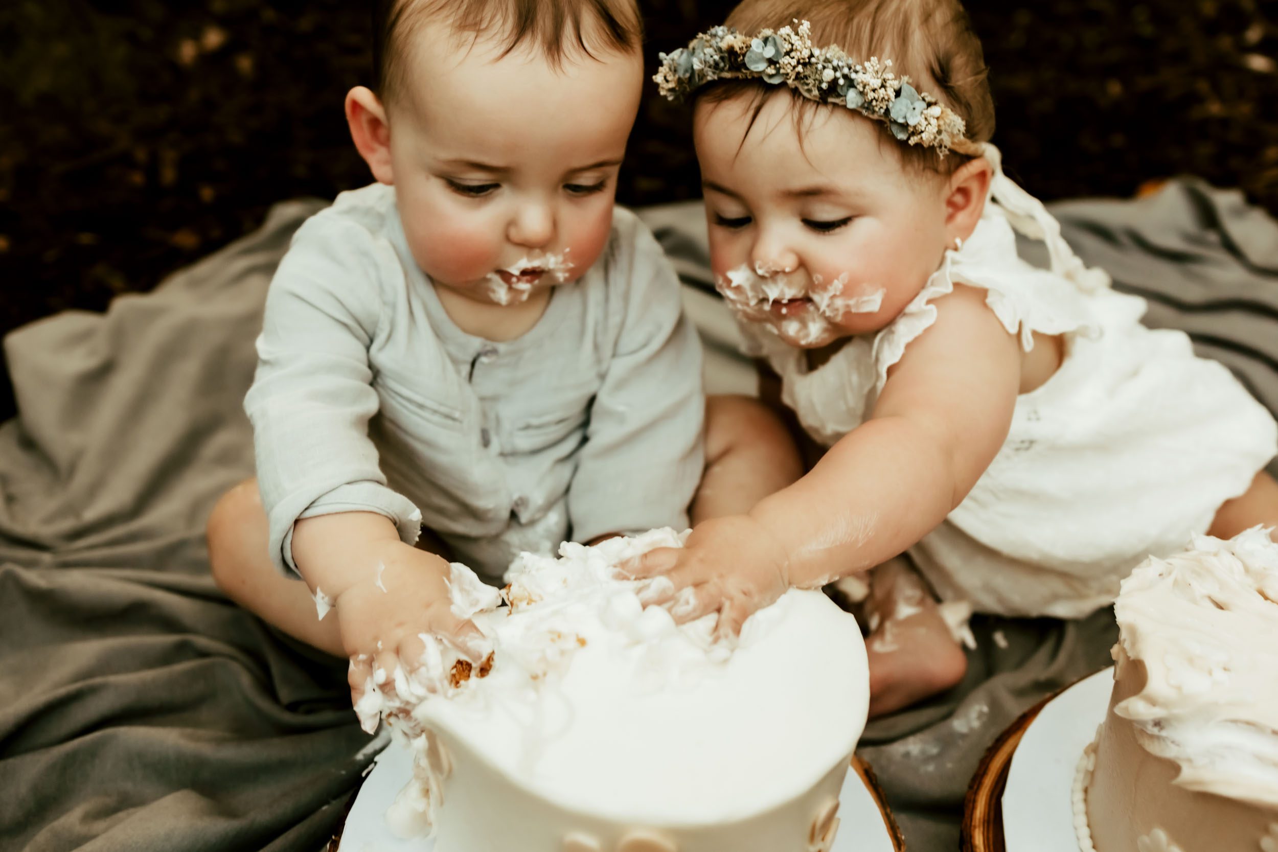 twins cake smash close up of them both with their hands in one cake