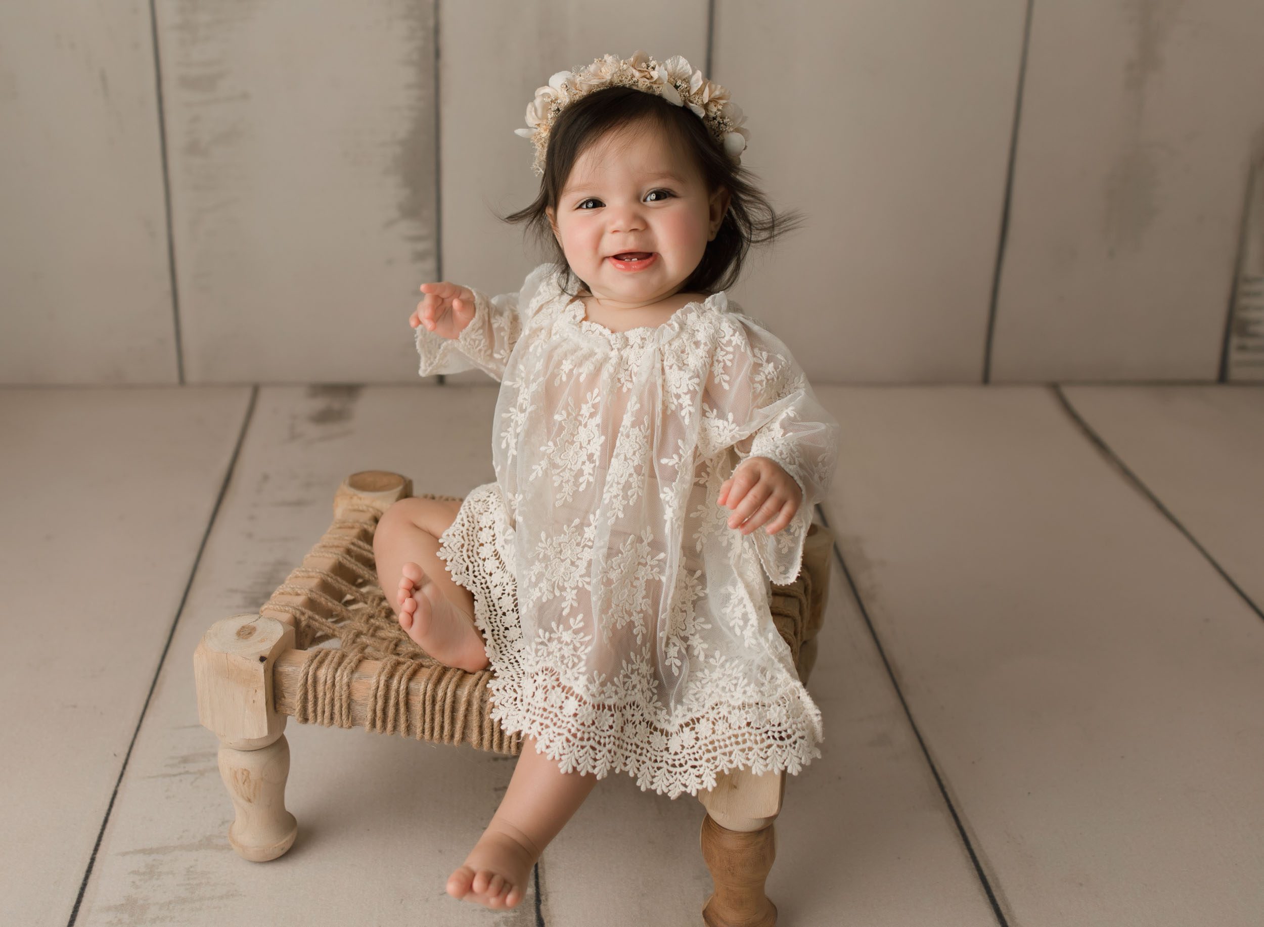Happy baby girl sitting on a stool wearing a beautiful lace outfit