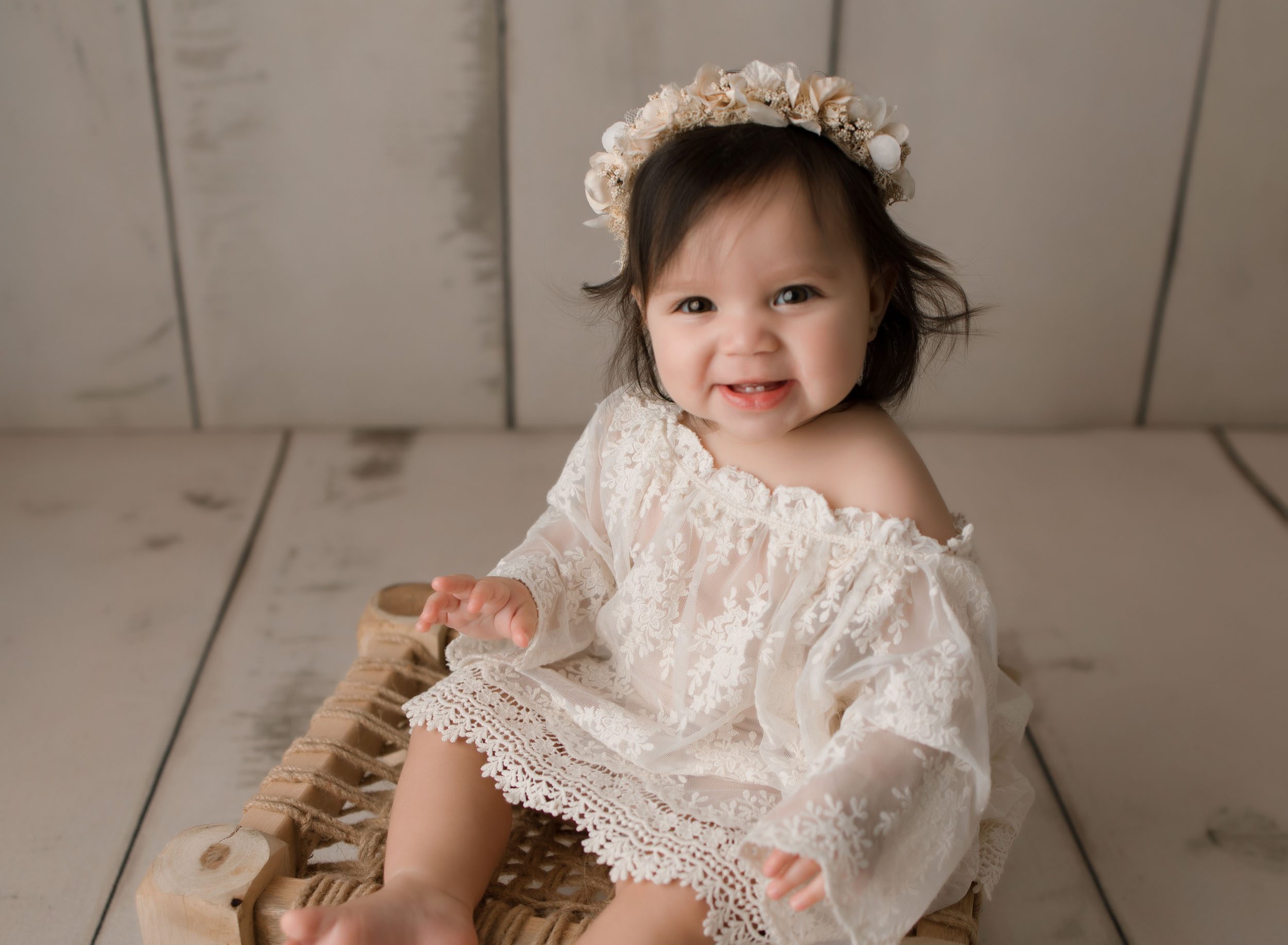 6 month old baby girl wearing lace outfit sitting on stool