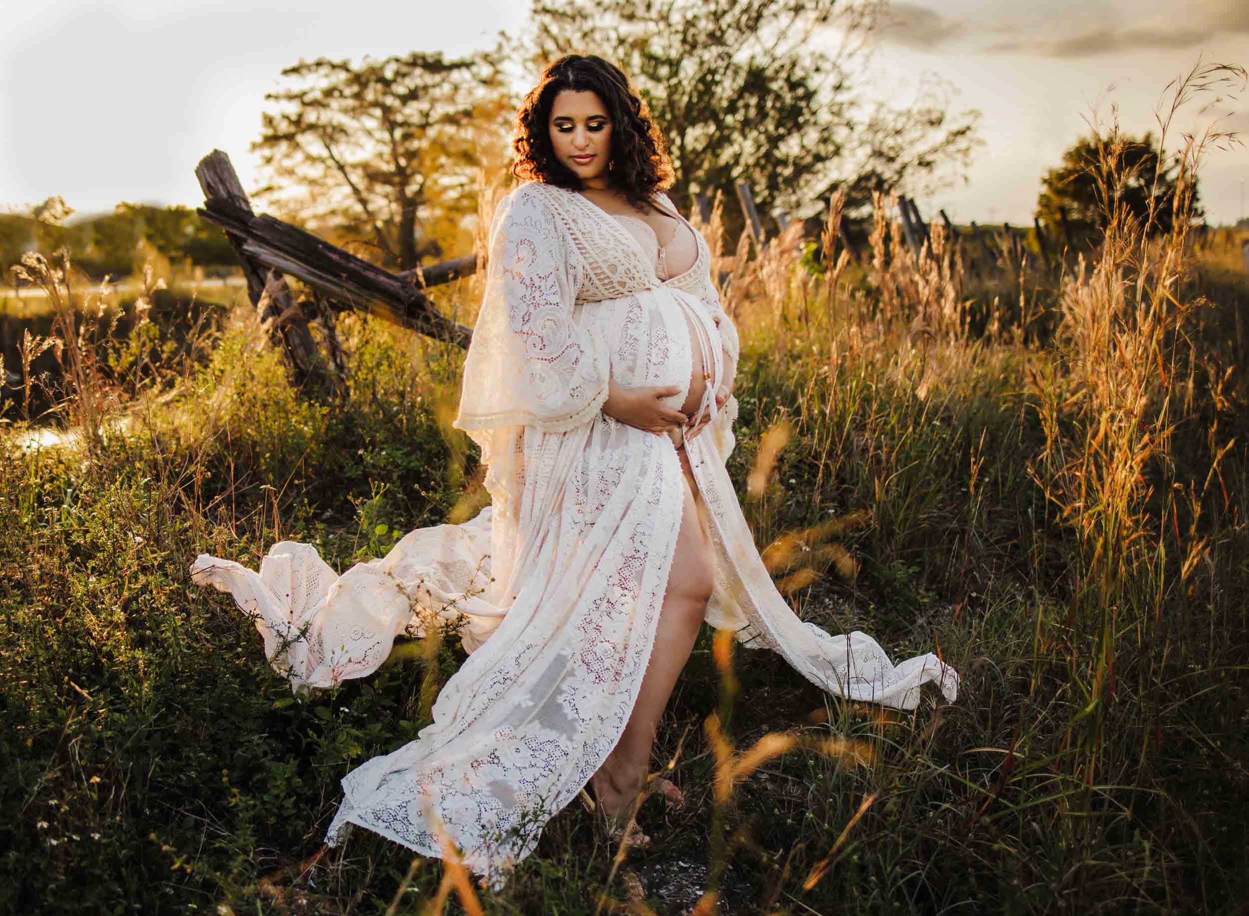 pregnant mom posing in a field at golden hour in long white dress during a boca raton maternity photoshoot