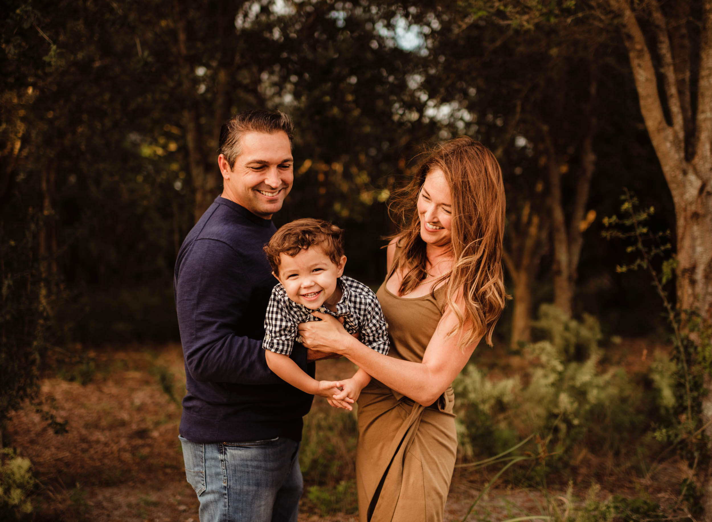 family of 3 tickling baby boy during outdoor family photoshoot in Boca Raton