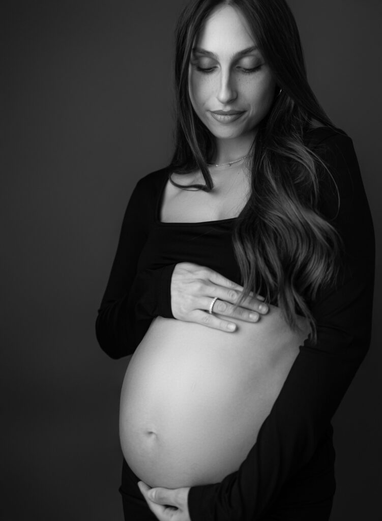 Black and white image of mom's face and her baby bump for studio photos