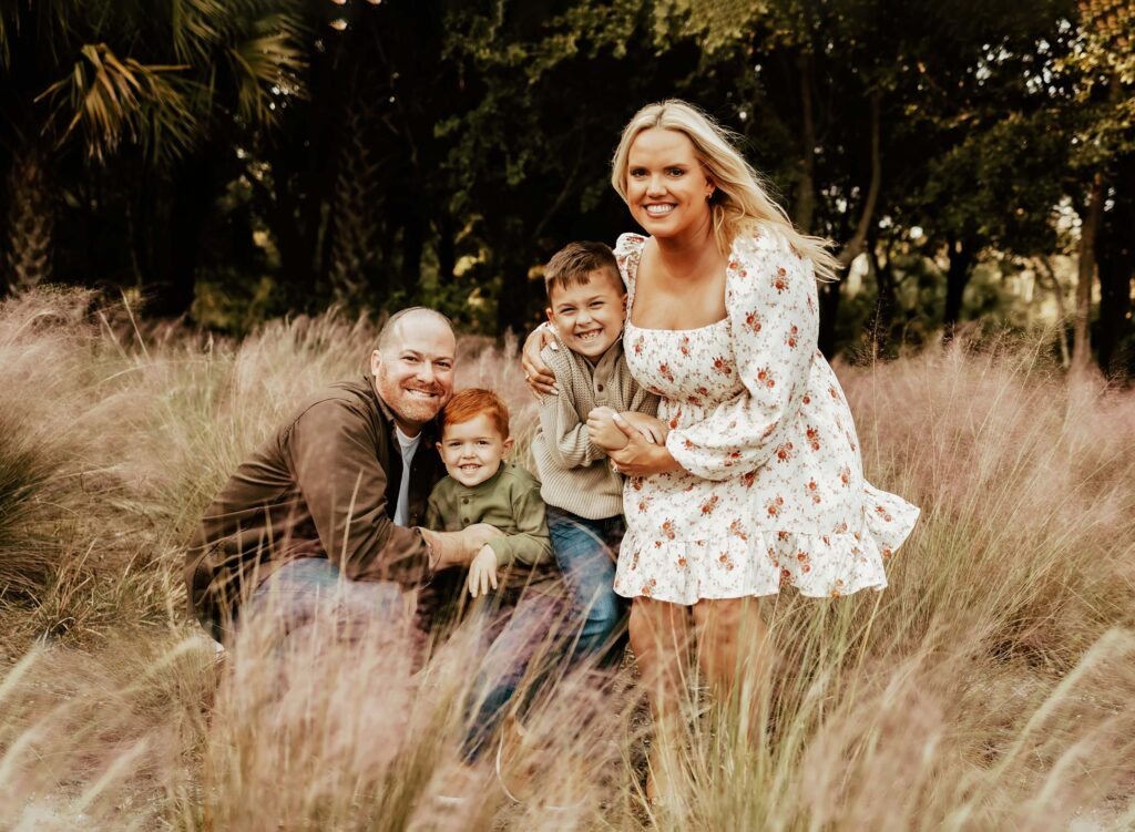 Family of four in golden grass field for family photos in Boca Raton