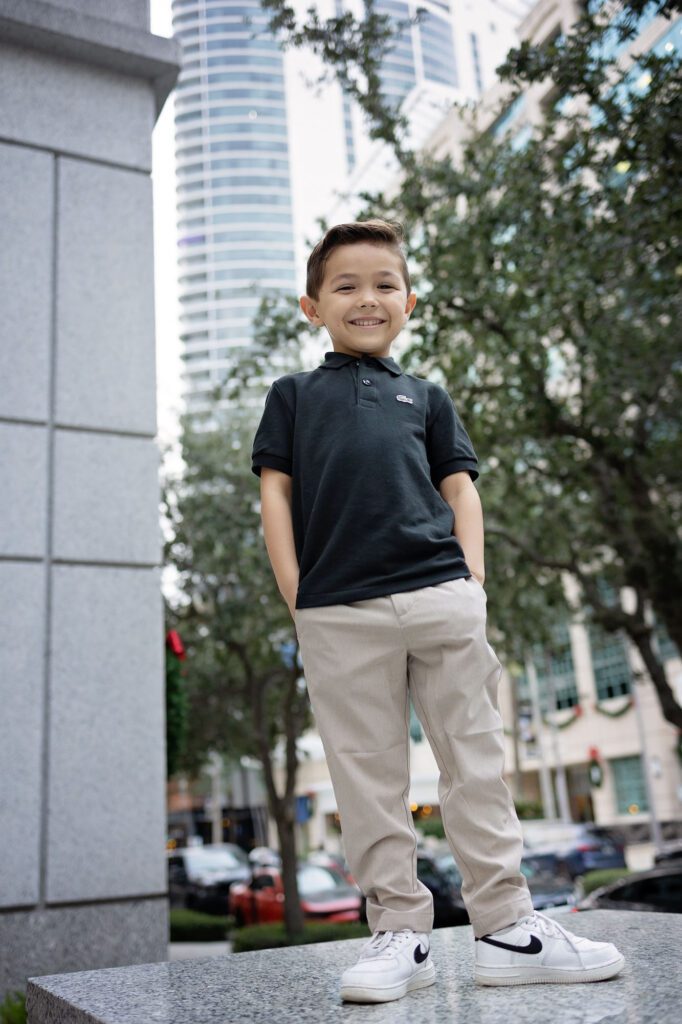 boy standing on wall in front of a skyscraper in Fort Lauderdale.