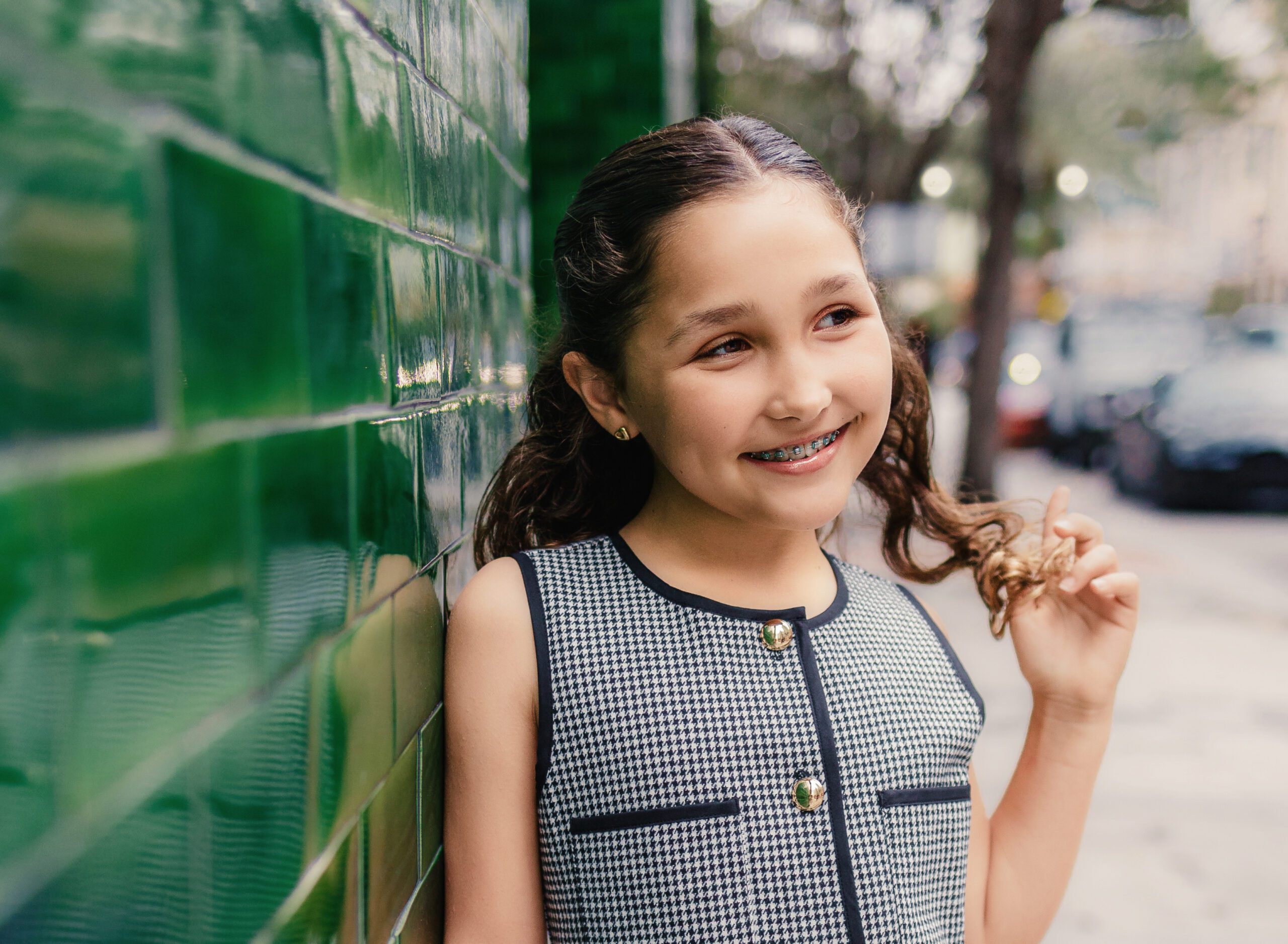 Tween girl standing against green tile wall, Las Olas Blvd