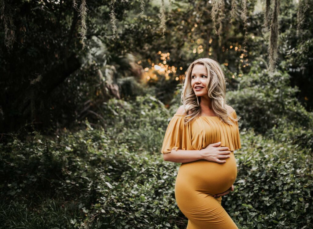pregnant mom touching her belly during an outdoor forest maternity photography session.