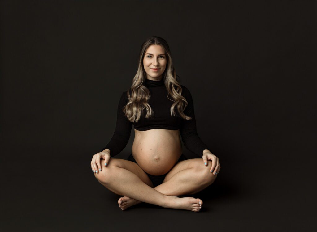 expecting mom in black crop top sitting on floor for photoshoot