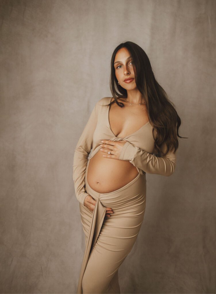 studio maternity photo of mom wearing dress exposing her baby bump