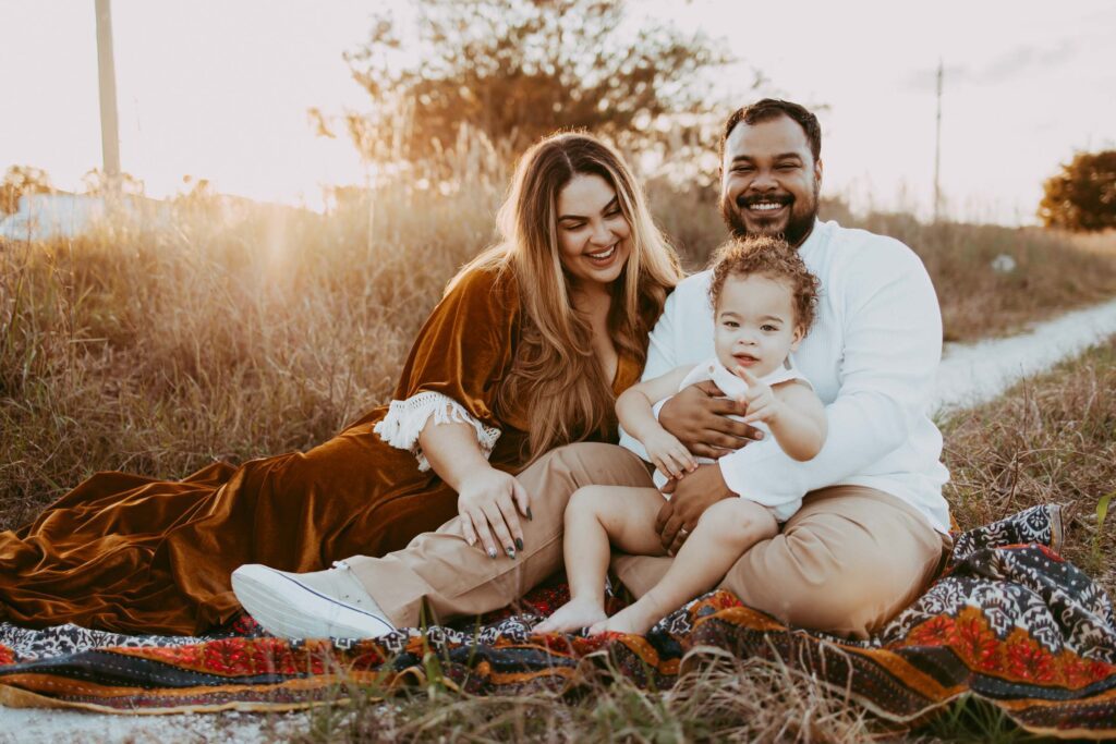 Baby boy sitting on dads lap for a golden hour photoshoot