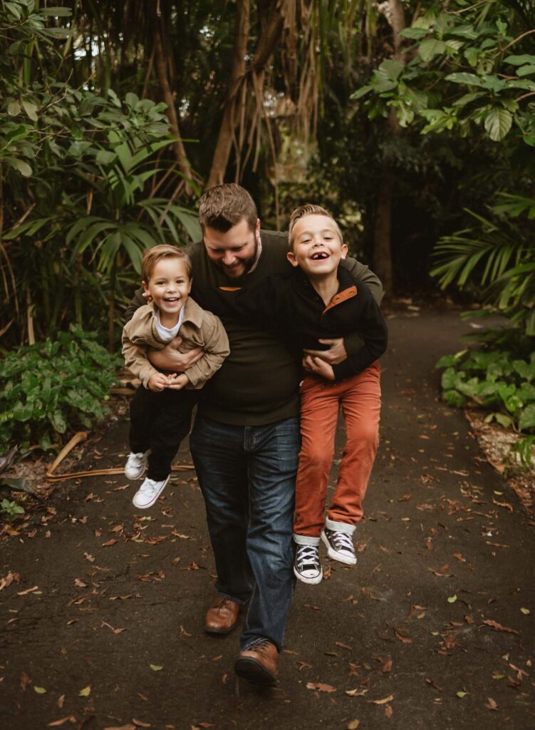 Dad running carrying a son under each arm while son's laugh is a great family photo idea
