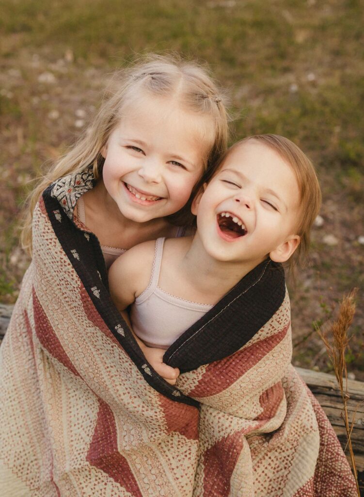 Sisters snuggled in blanket being silling pose idea for family photos