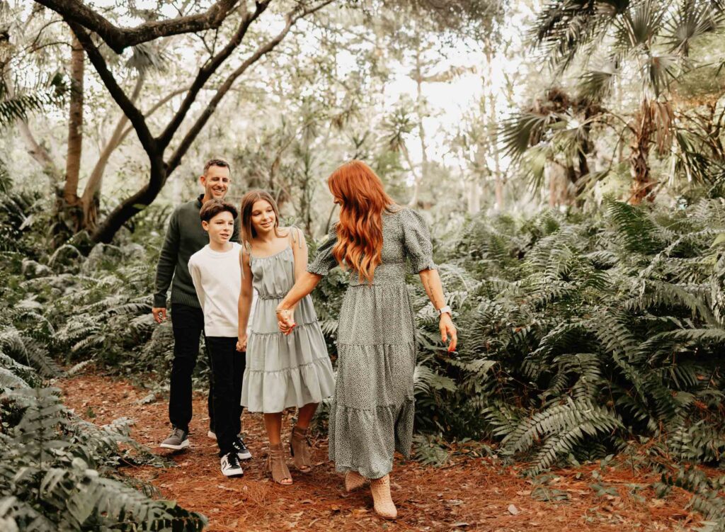 Family of 4 walking through lush park with mom leading the way