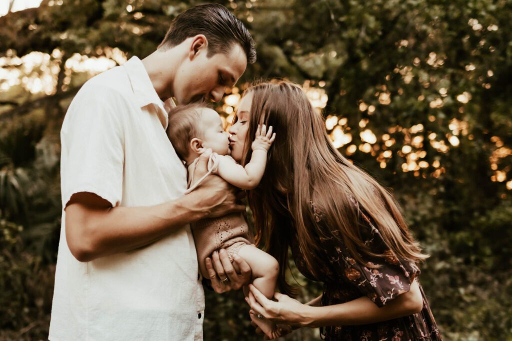 Dad holding baby towards mom so she can give baby a kiss.