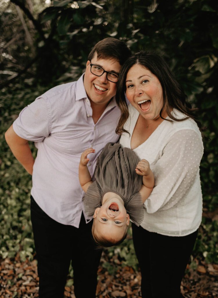 Parents holding toddler upside down being silly and having fun at photoshoot in Parkland