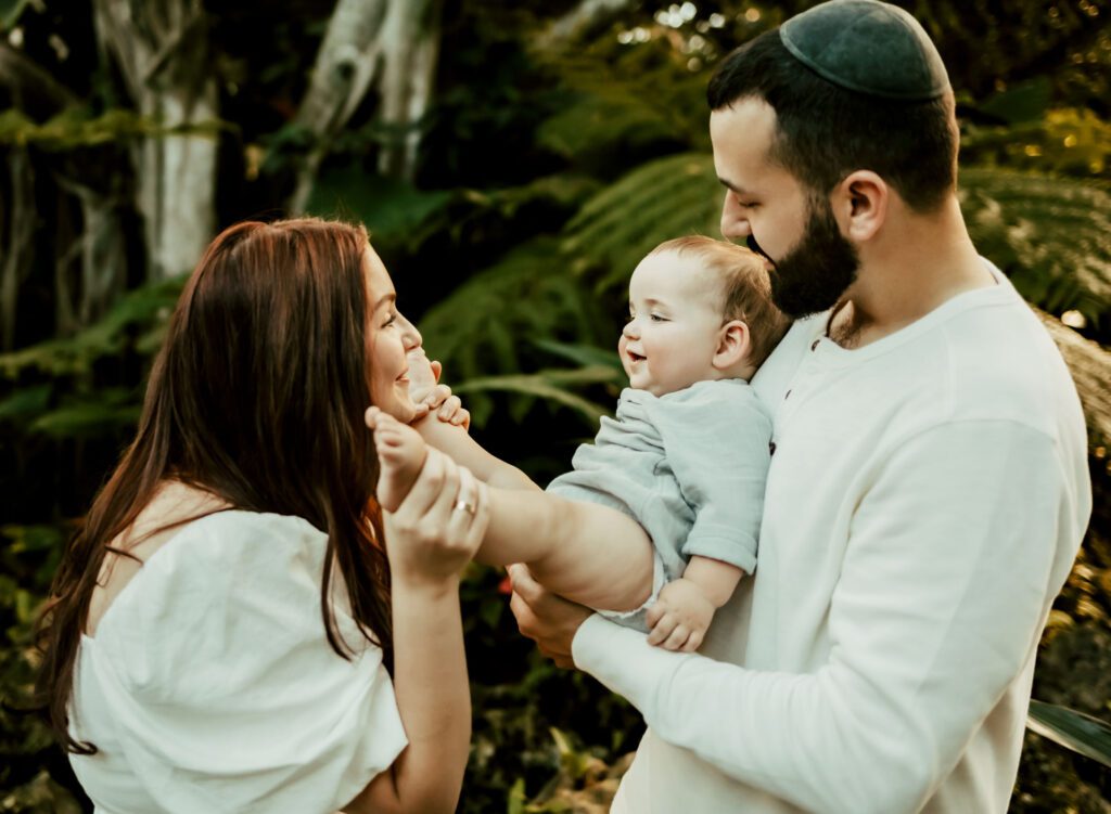 Dad holding baby towards mom and mom kissing baby's feet.