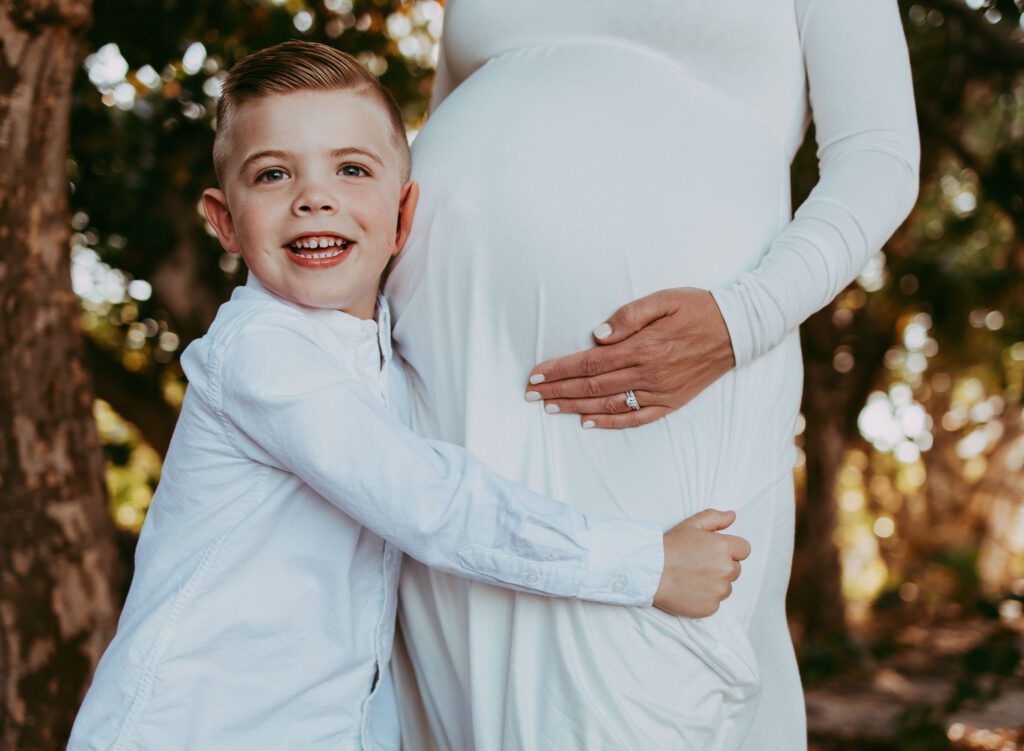 older sibling hugging mom's legs and resting head on baby bump