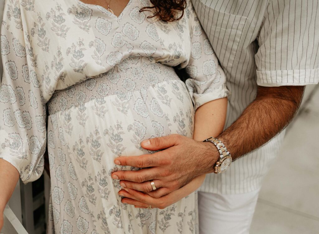 close up of couple holding baby bump together