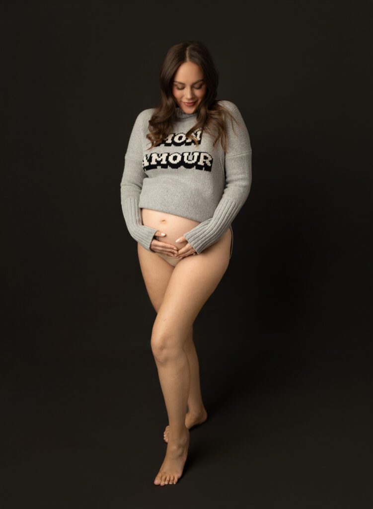 maternity photoshoot ideas of mom mom wearing chunky sweater in studio