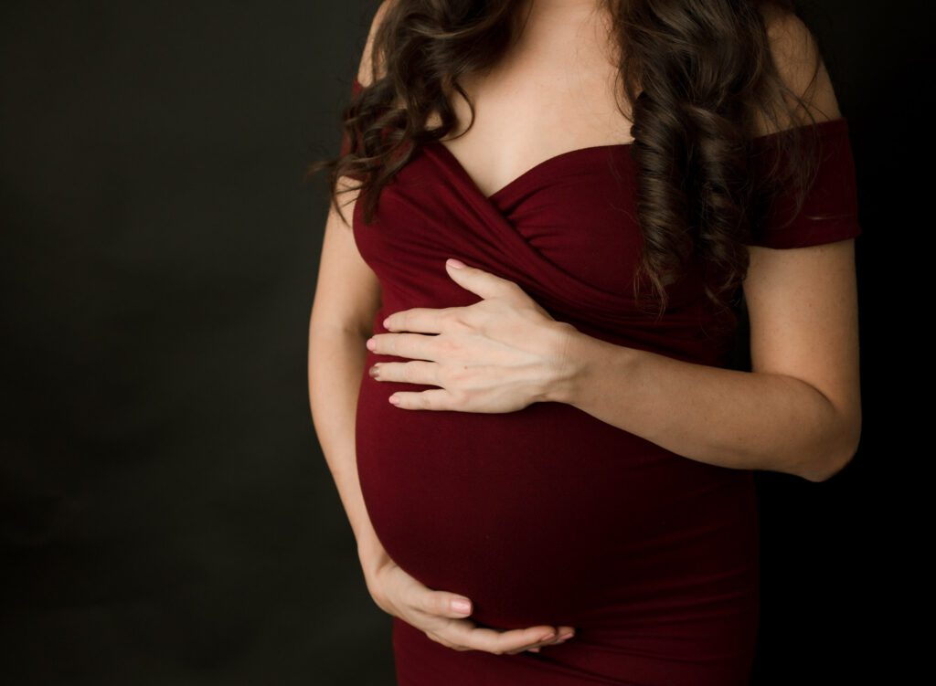 close up of pregnant belly and moms hands shot in a photo studio