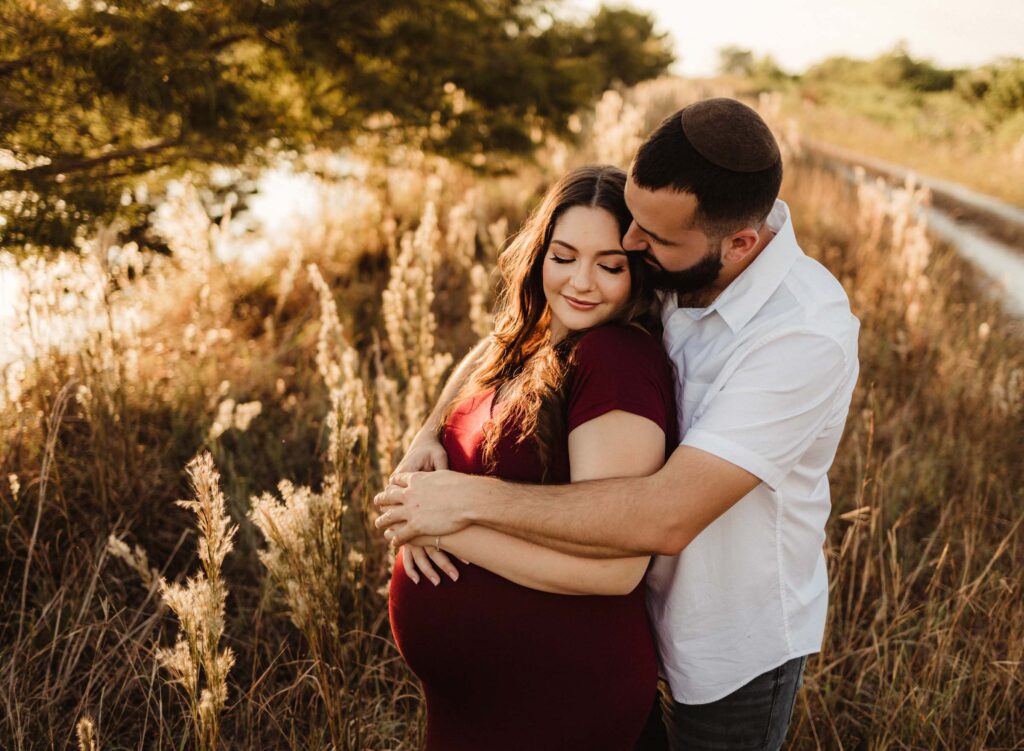 expectant couple snuggled together with husband giving bear hug showing couples maternity photoshoot ideas