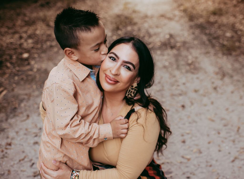 Son giving mom a little kiss on the cheek at their outdoor family photo session in Boca Raton