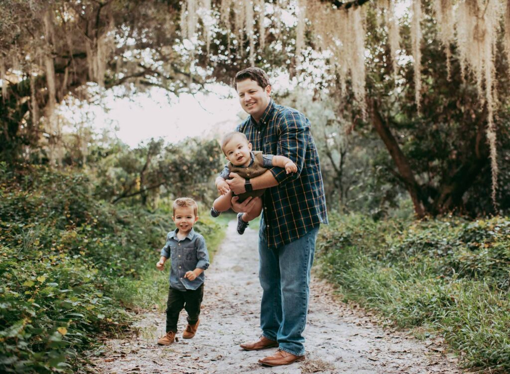 Dad holding his baby like an airplane swinging him high in the air at their family photoshoot in Parkland