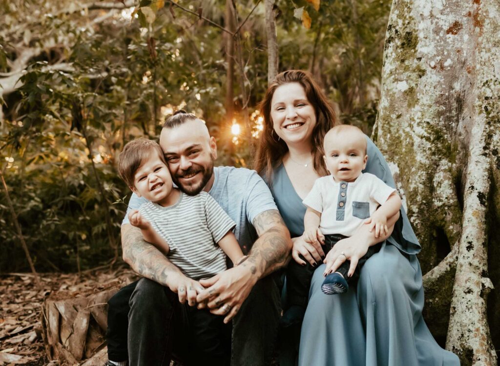 Family golden hour photoshoot in Boca Raton with family of four sitting on big tree roots