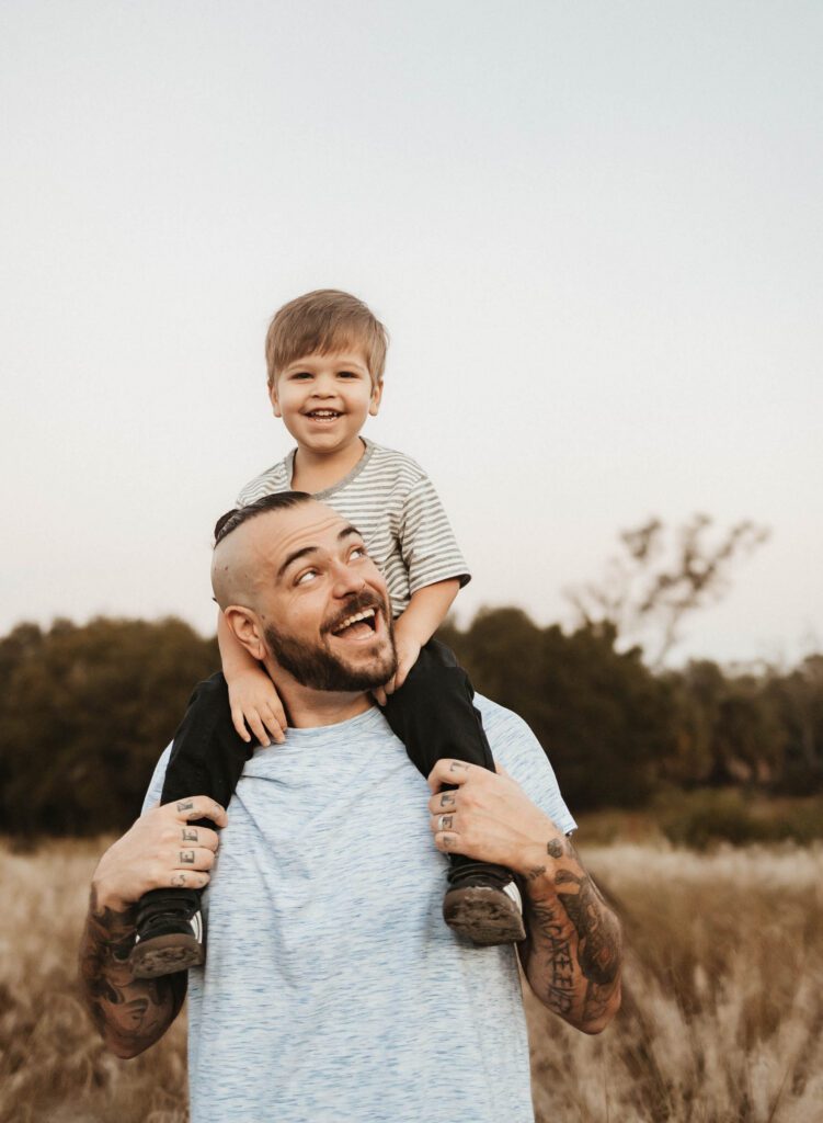 Todder on dads shoulders laughing in Boca Raton for their outdoor family photoshoot.