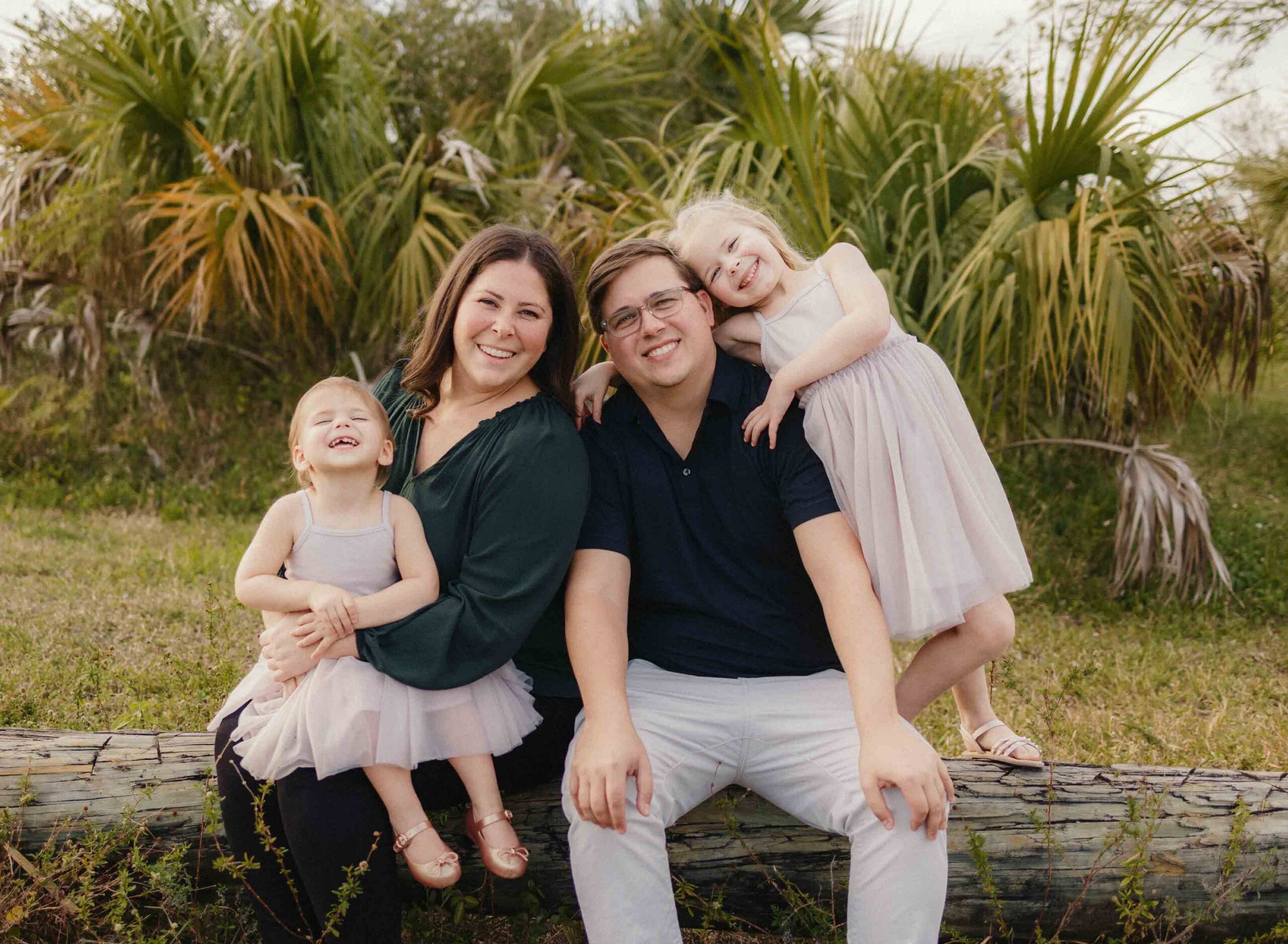 Family sitting on a log in the park for their family photoshoot in Parkland
