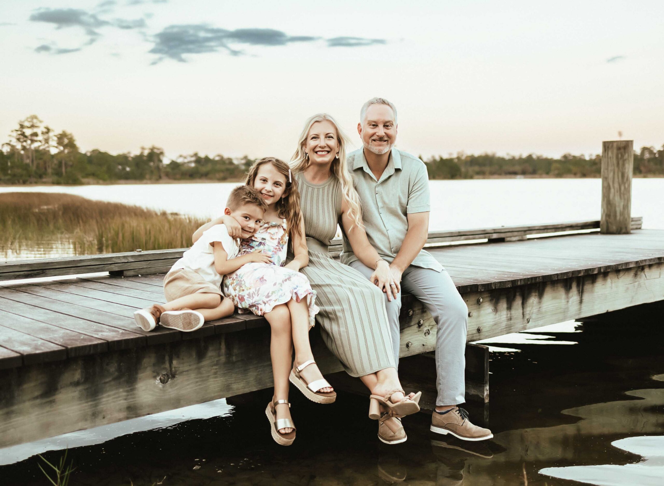 Mom, dad, daughter and son sititng on a dock in West Palm Beach at their family photosession