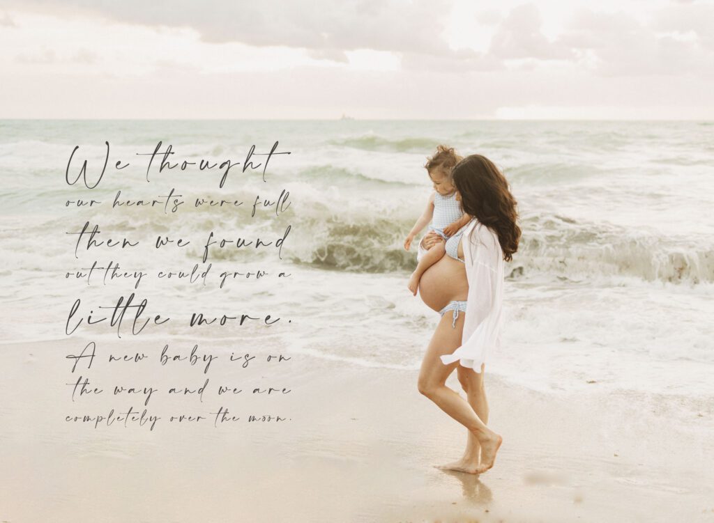 Pregnancy announcement photo example of mom holding older sister walking on the beach.