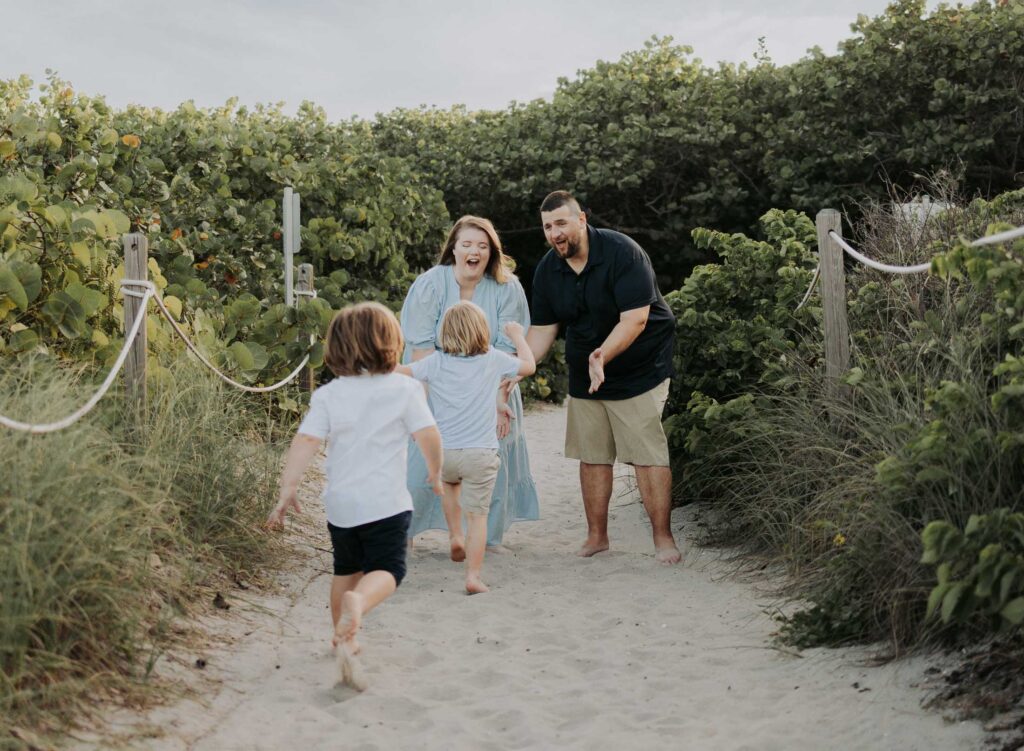 Family on the beach with 2 little boys running towards their parents